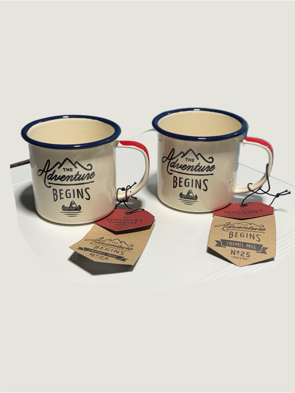The Adventure Begins Cream Enamel Mug with Navy Rim and Red Handle
